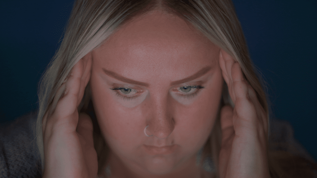 A woman stares at a computer screen and looks stressed